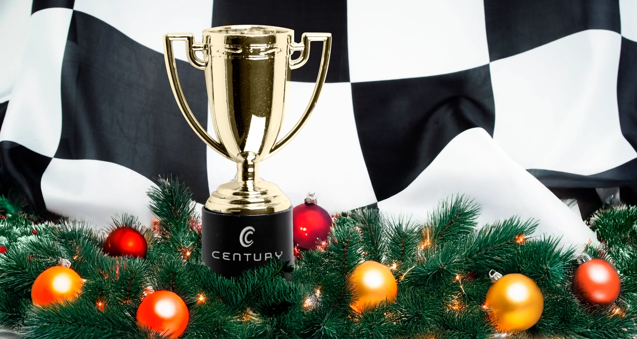 A shiny gold trophy stands on a festive green garland decorated with colorful ornaments, set against a checkered black and white backdrop.